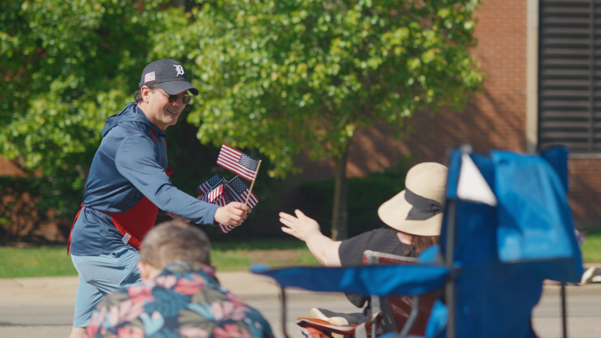 Michael Sawicky handing a small American flag to a seated person outdoors near a table and blue canopy