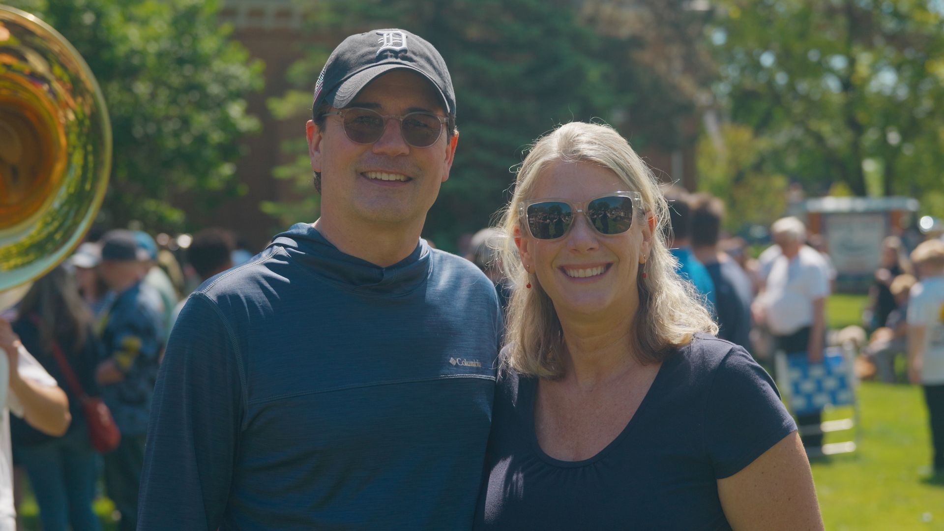 Michael Sawicky memorial day parade. smiling people wearing sunglasses stand outdoors at a sunny park event.