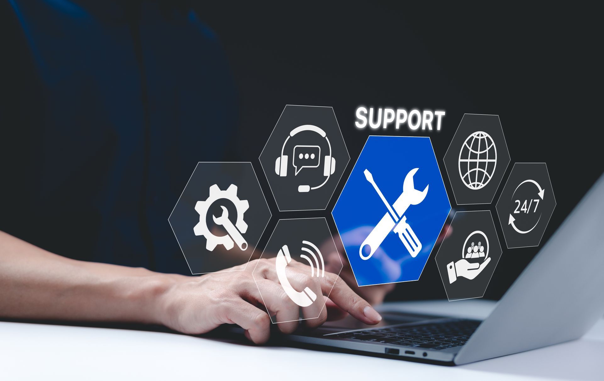 Hands typing on laptop with floating support icons and blue wrench-and-screwdriver symbol
