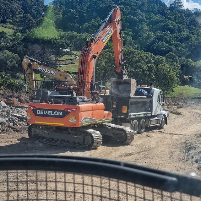 A truck is driving down a dirt road next to a pile of trash.