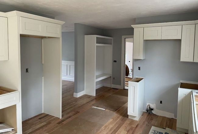 Unfinished interior room with white built-in cabinetry and light gray walls under construction.