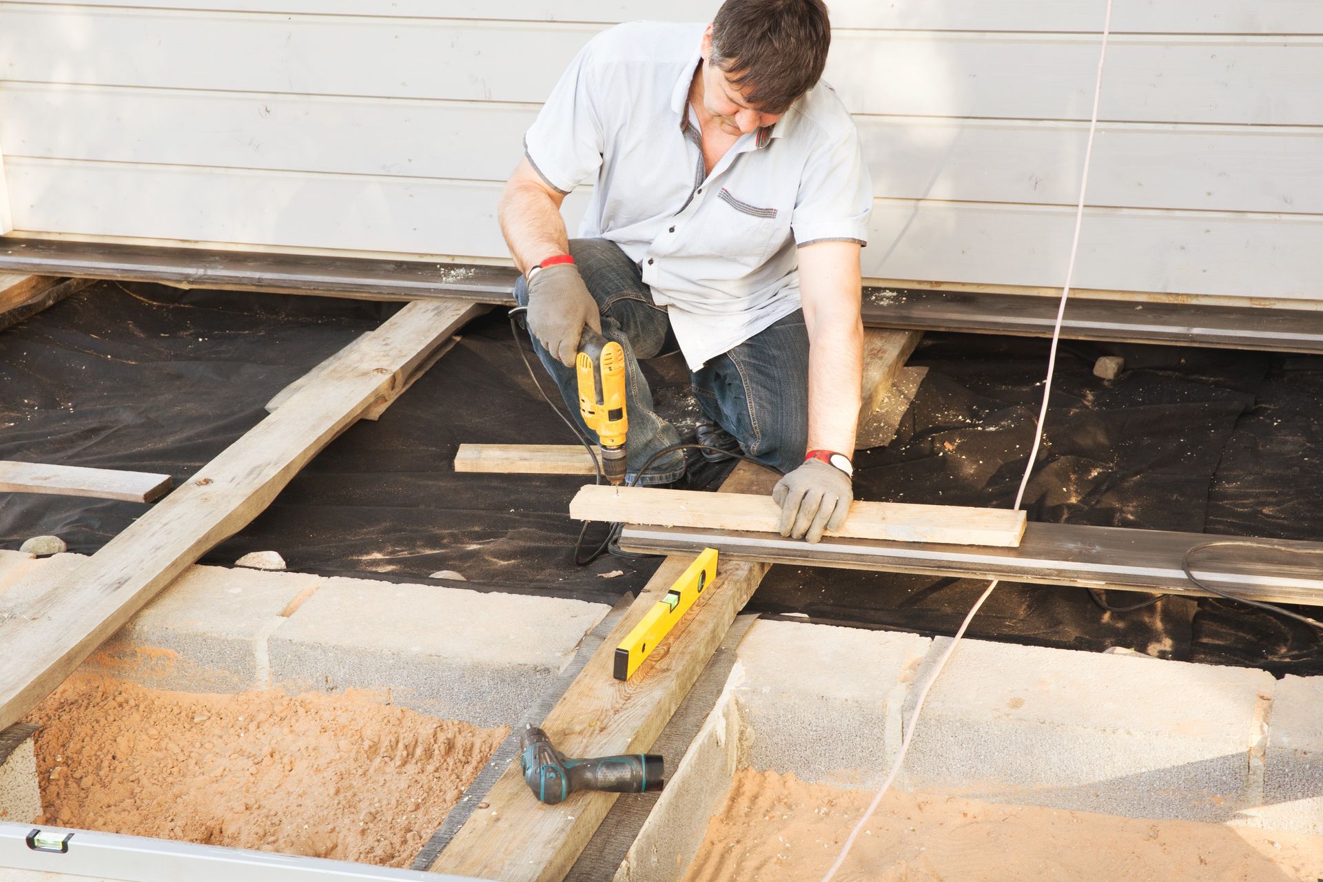Carpenter installing decking boards on a residential home deck.