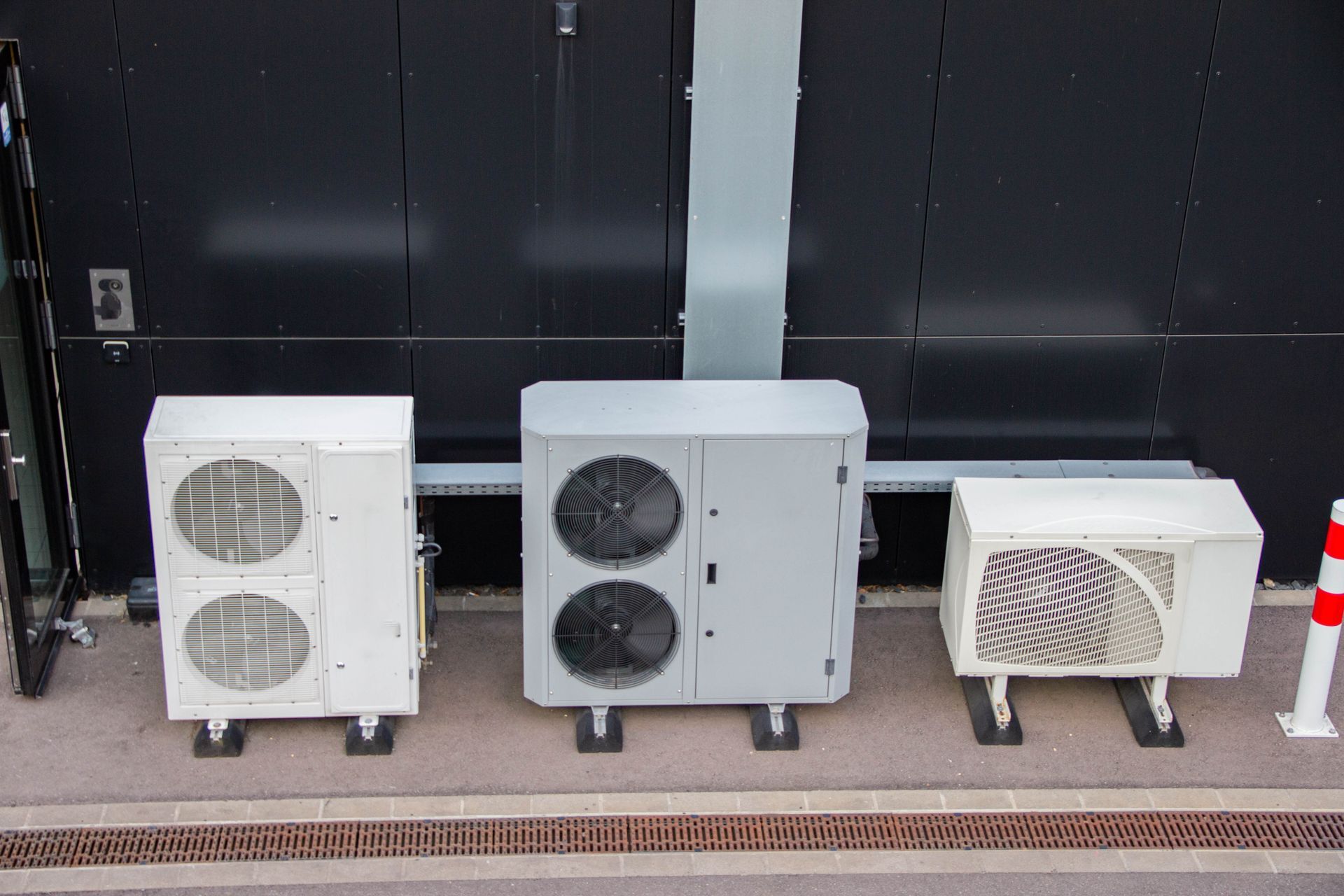 Three distinct air conditioning units positioned outside a building.