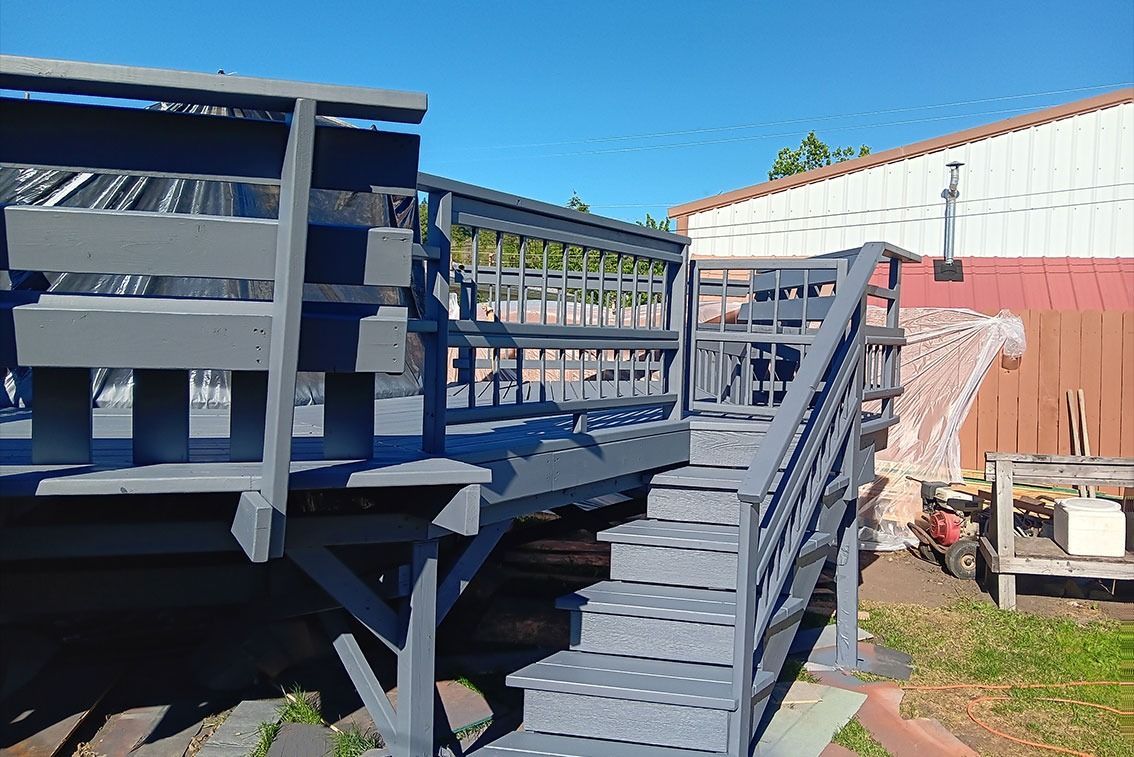 Outdoor wheelchair ramp and raised wooden walkway beside buildings under a blue sky
