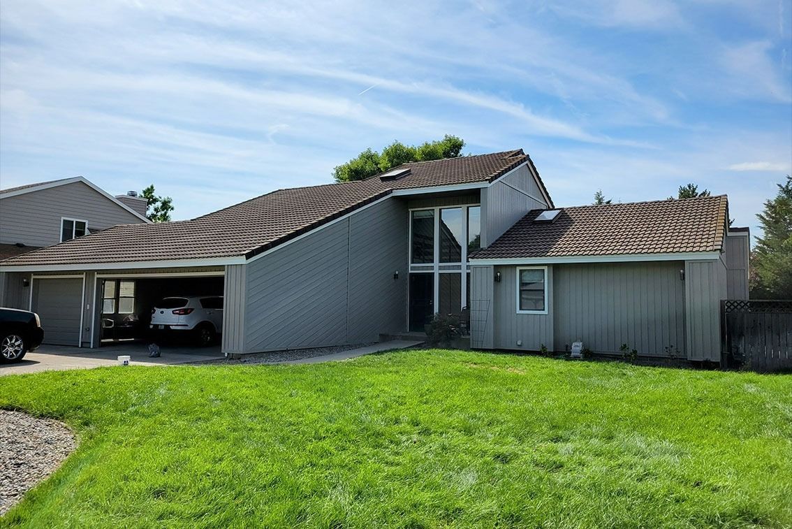 Modern gray house with a sloped roof and green lawn under a blue sky