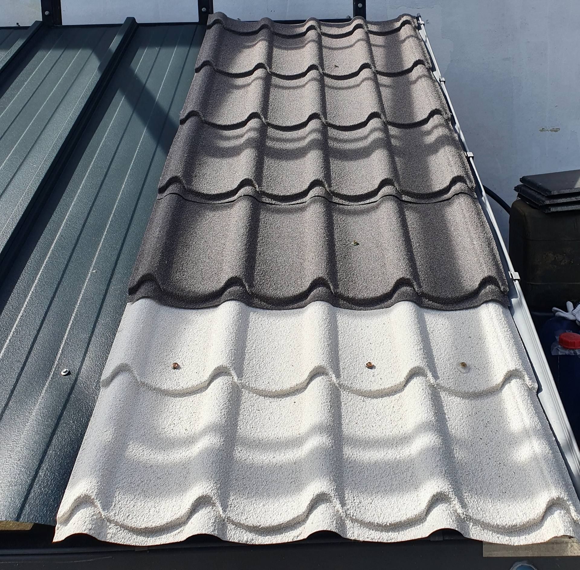 Two-tone metal roof panels, dark gray above and light gray below, shown in close-up.