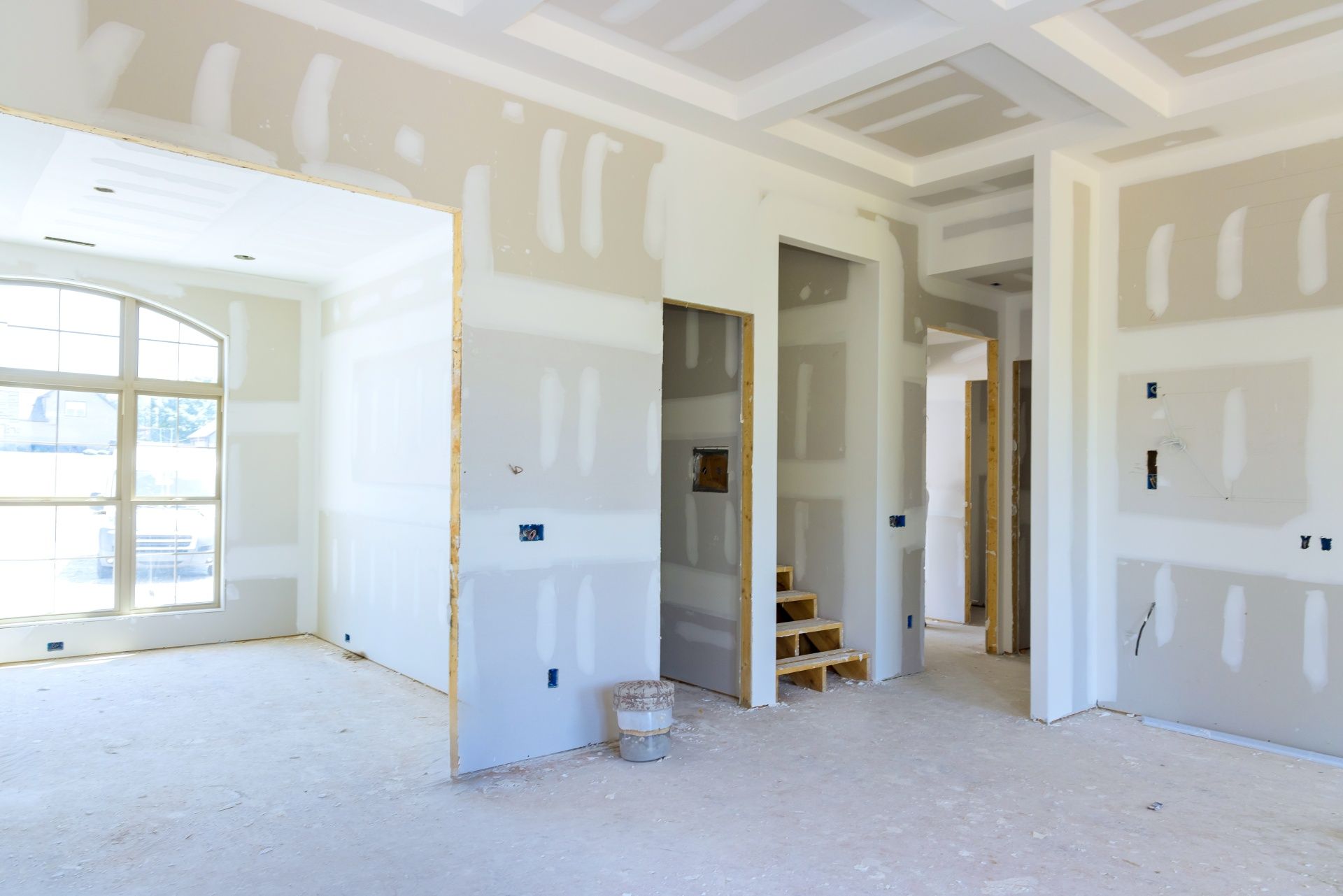 Renovated interior room with drywall, doorways, and a large window letting in daylight