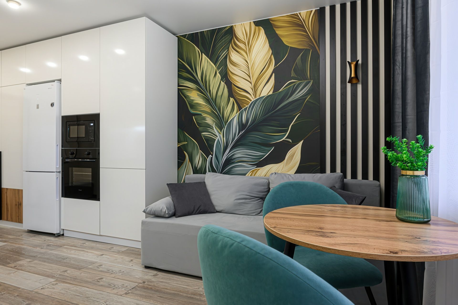 Modern living room with a gray sofa, tropical wall art, teal chair, and built-in white cabinetry
