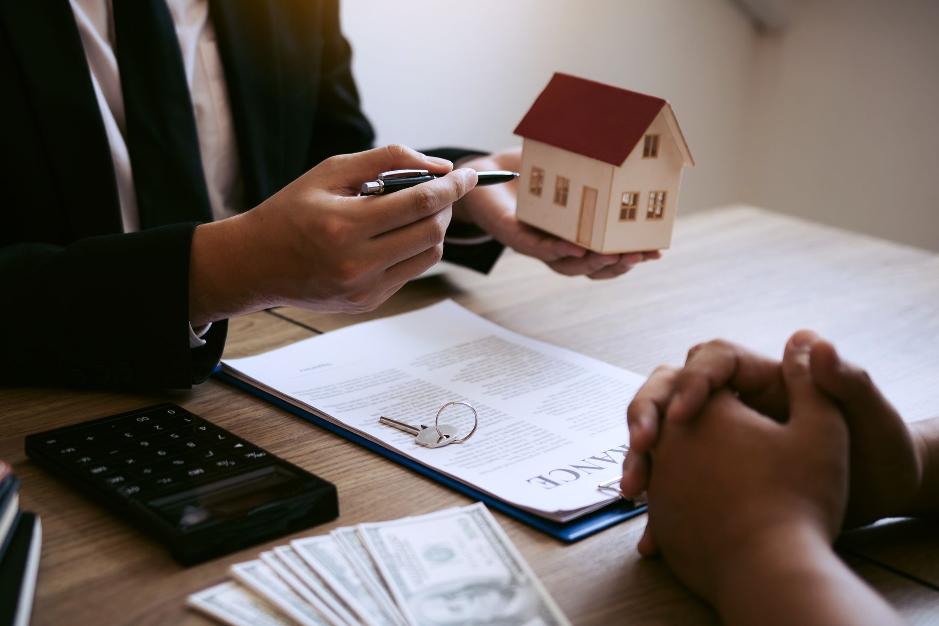 Real estate agent showing house model, pointing to document, with buyer, keys, money.