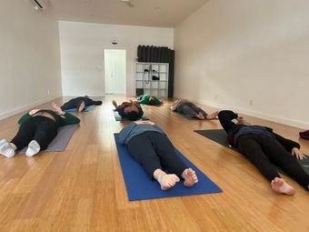 A group of people are laying on yoga mats in a room.