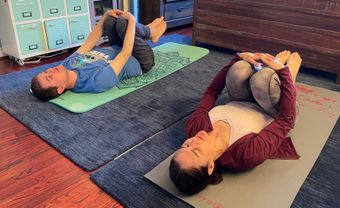 A man and a woman are laying on yoga mats in a living room.