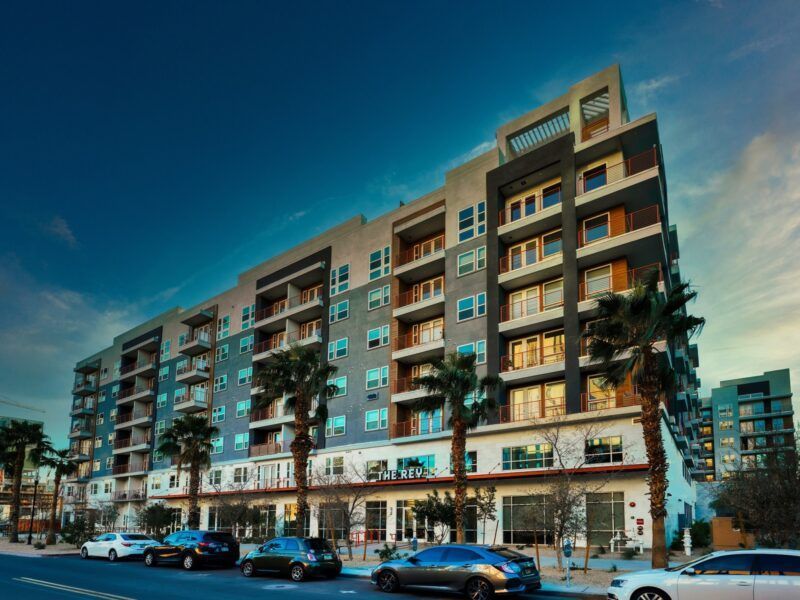 A large apartment building with cars parked in front of it.