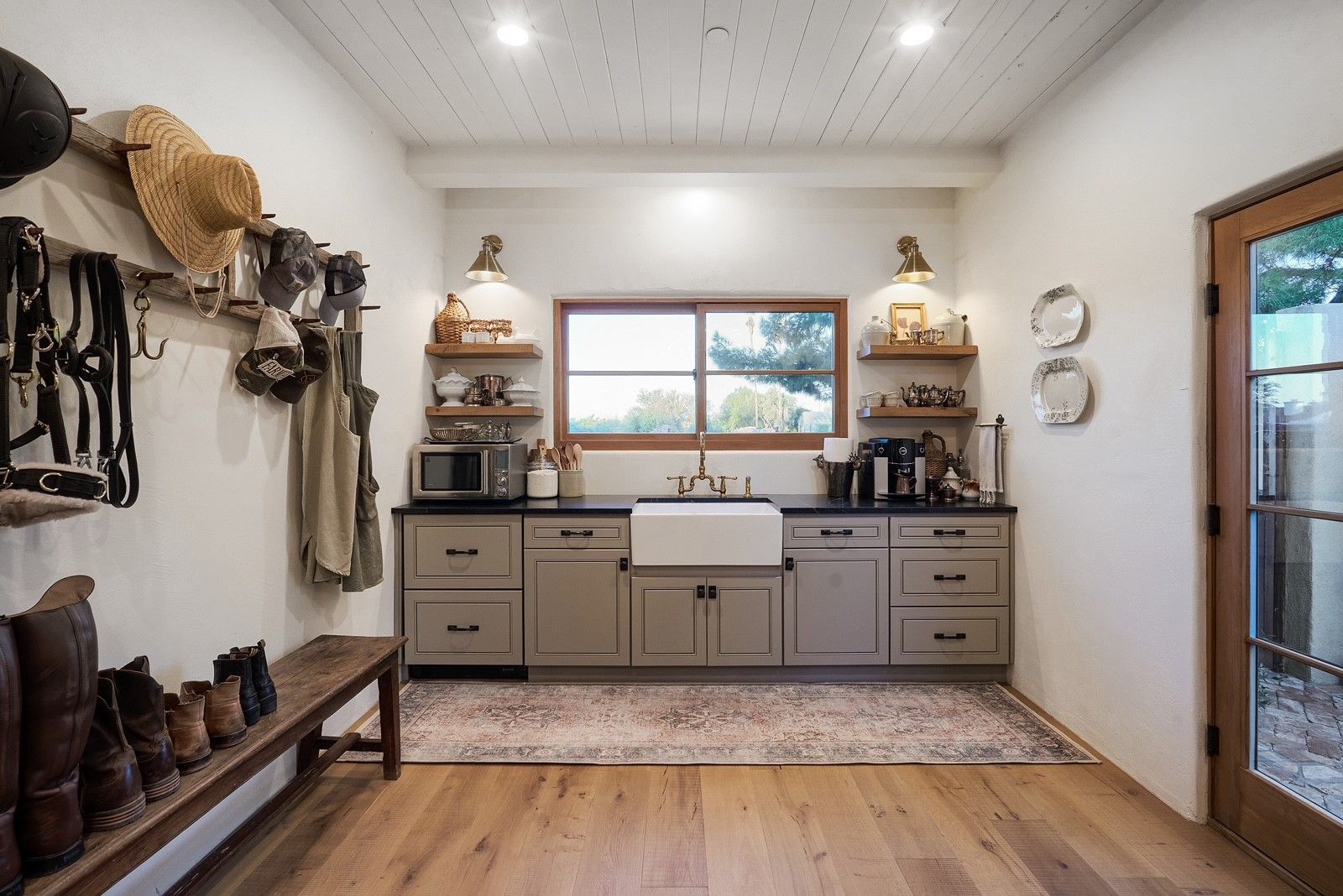 A kitchen with a sink , cabinets , shelves and a window.