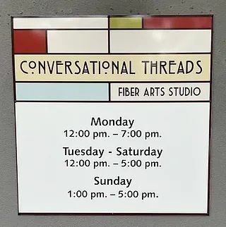 Sign for Conversational Threads Fiber Arts Studio with business hours displayed