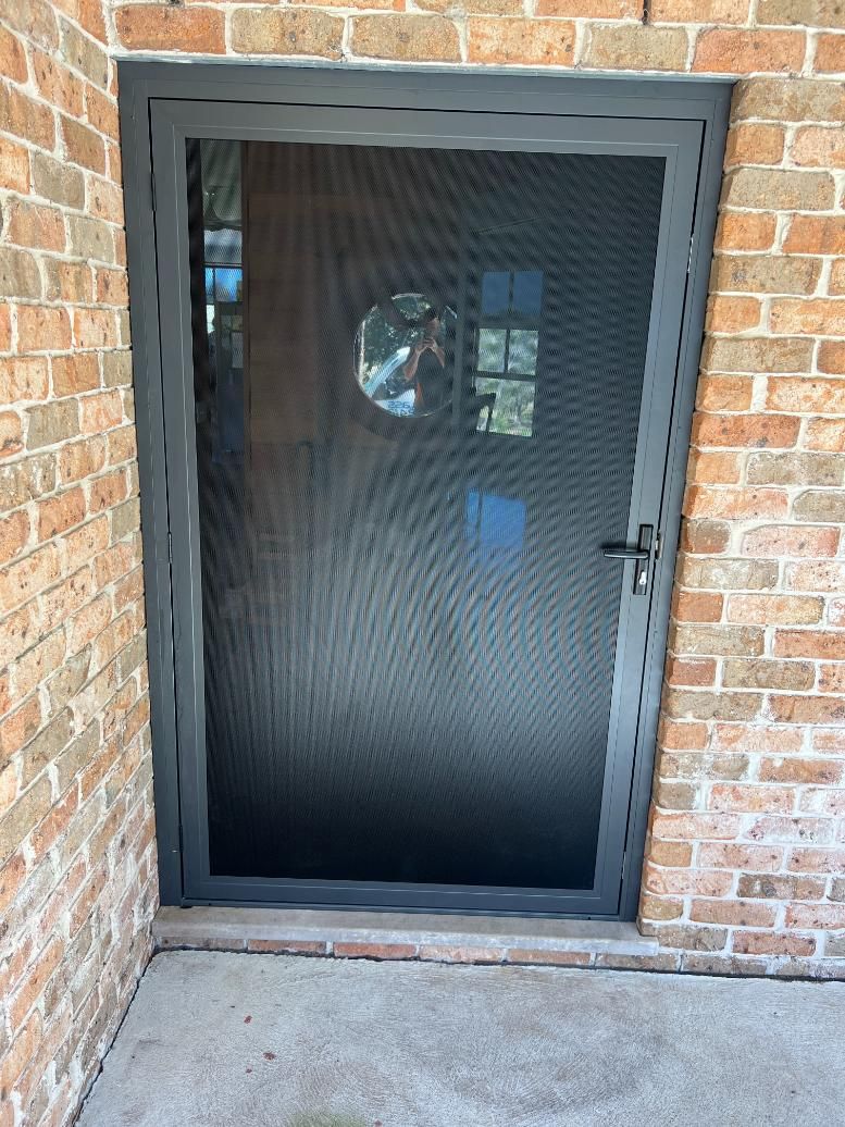 A Black Door Is Sitting In The Corner Of A Brick Building — Glass 24/7 In Taree, NSW