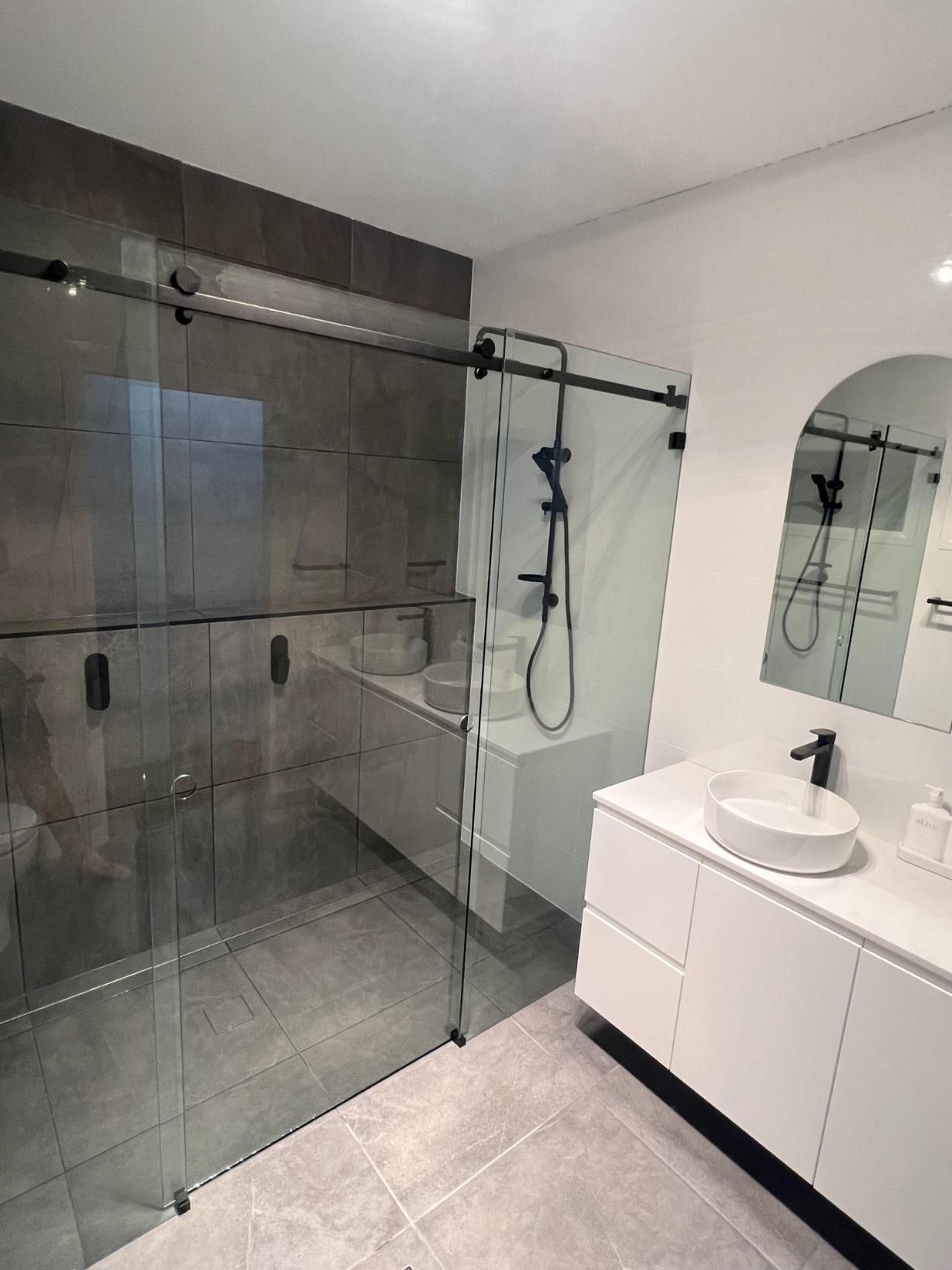 A Bathroom With A Sink And A Shower With Sliding Glass Doors — Glass 24/7 In Forster, NSW