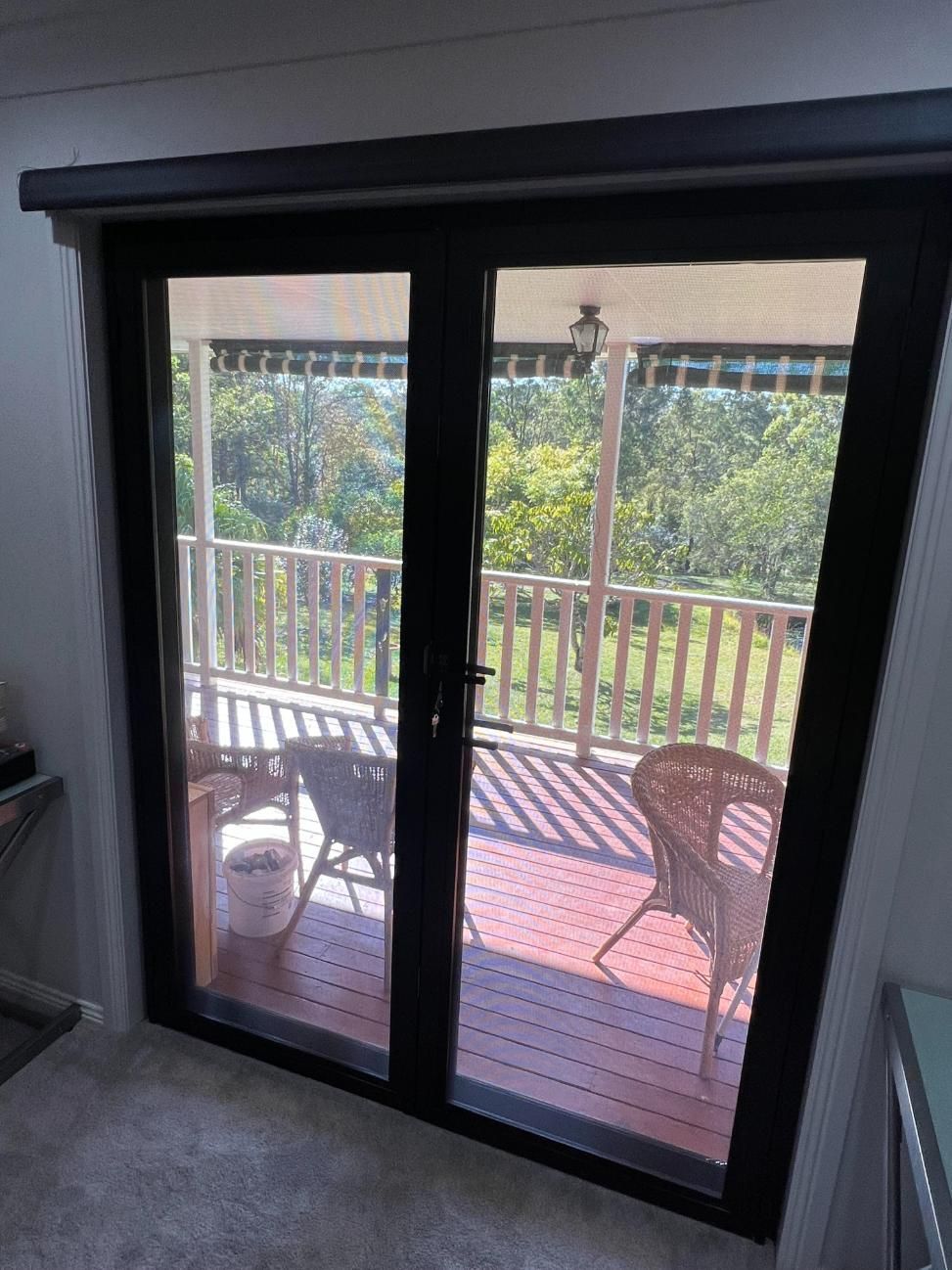 A Sliding Glass Door Leading To A Balcony With Chairs And A Table — Glass 24/7 In Taree, NSW