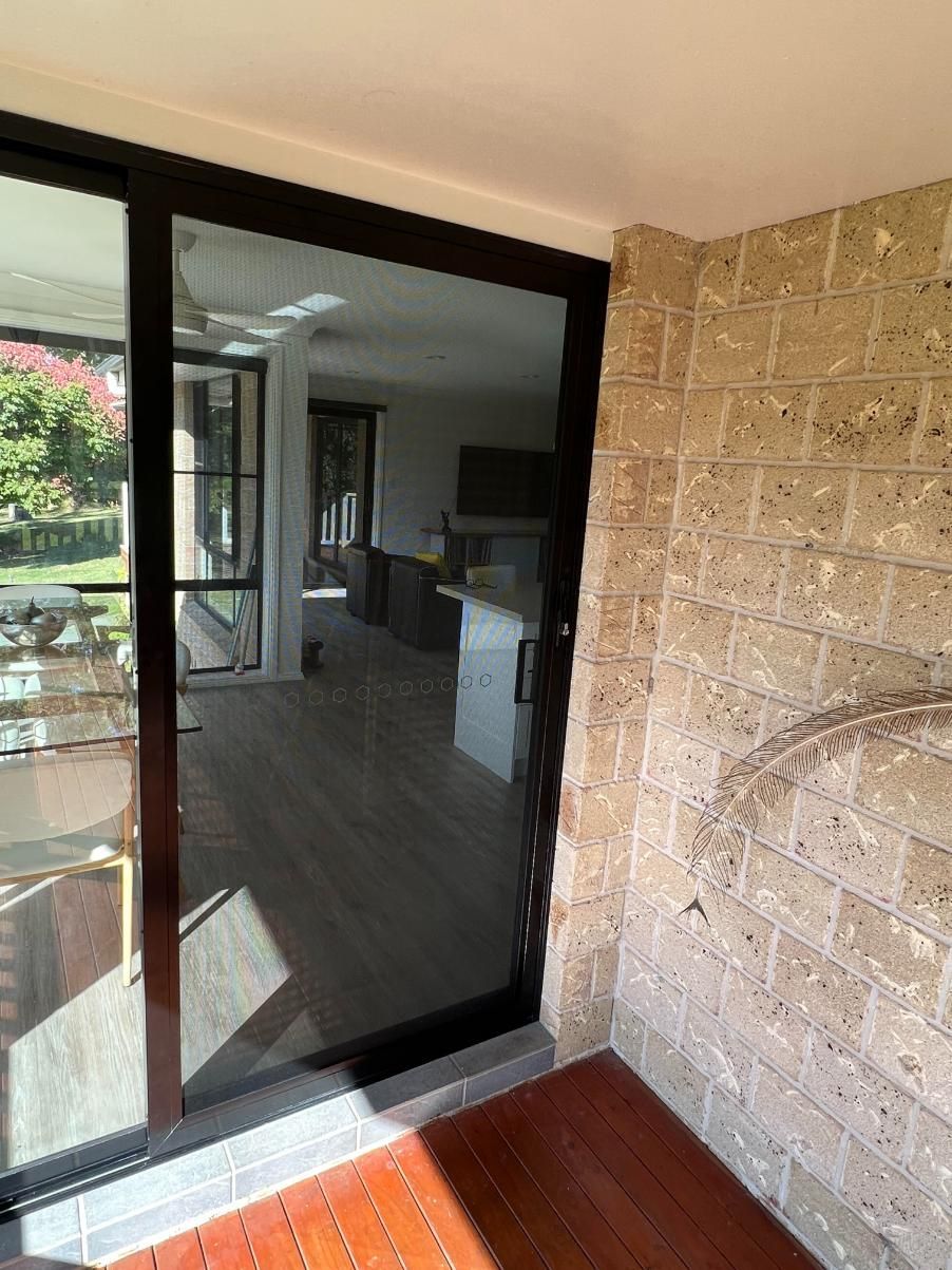 A Sliding Glass Door Is Open To A Living Room — Glass 24/7 In Taree, NSW