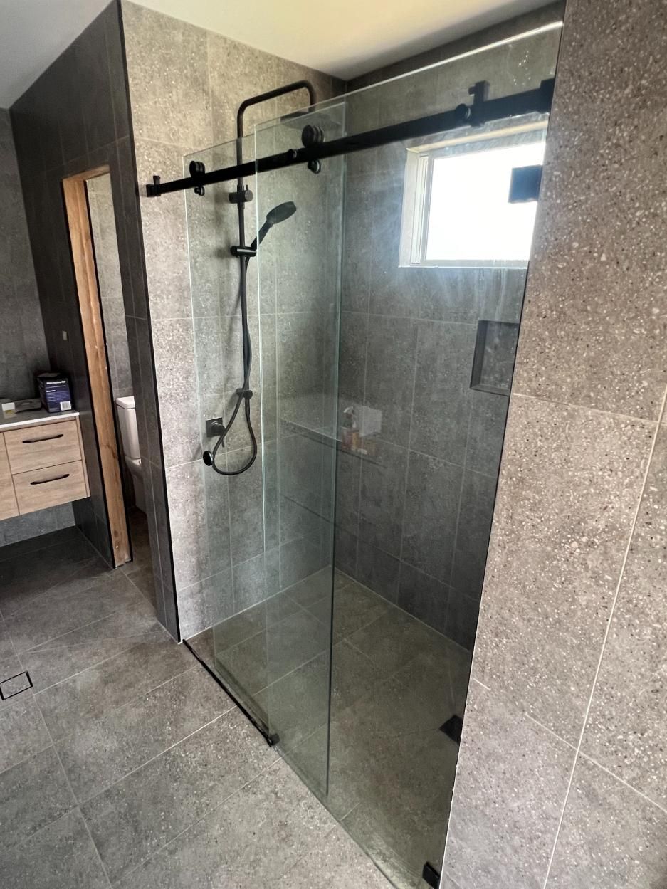A Bathroom With A Sliding Glass Shower Door And A Shower Head — Glass 24/7 In Taree, NSW