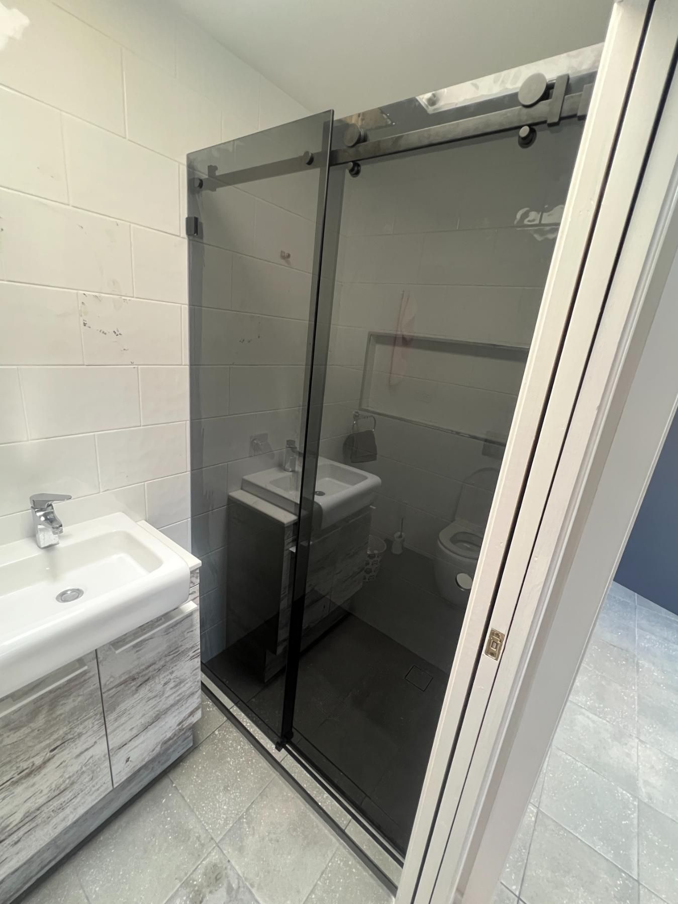 A Bathroom With A Sliding Glass Shower Door And A Sink — Glass 24/7 In Taree, NSW