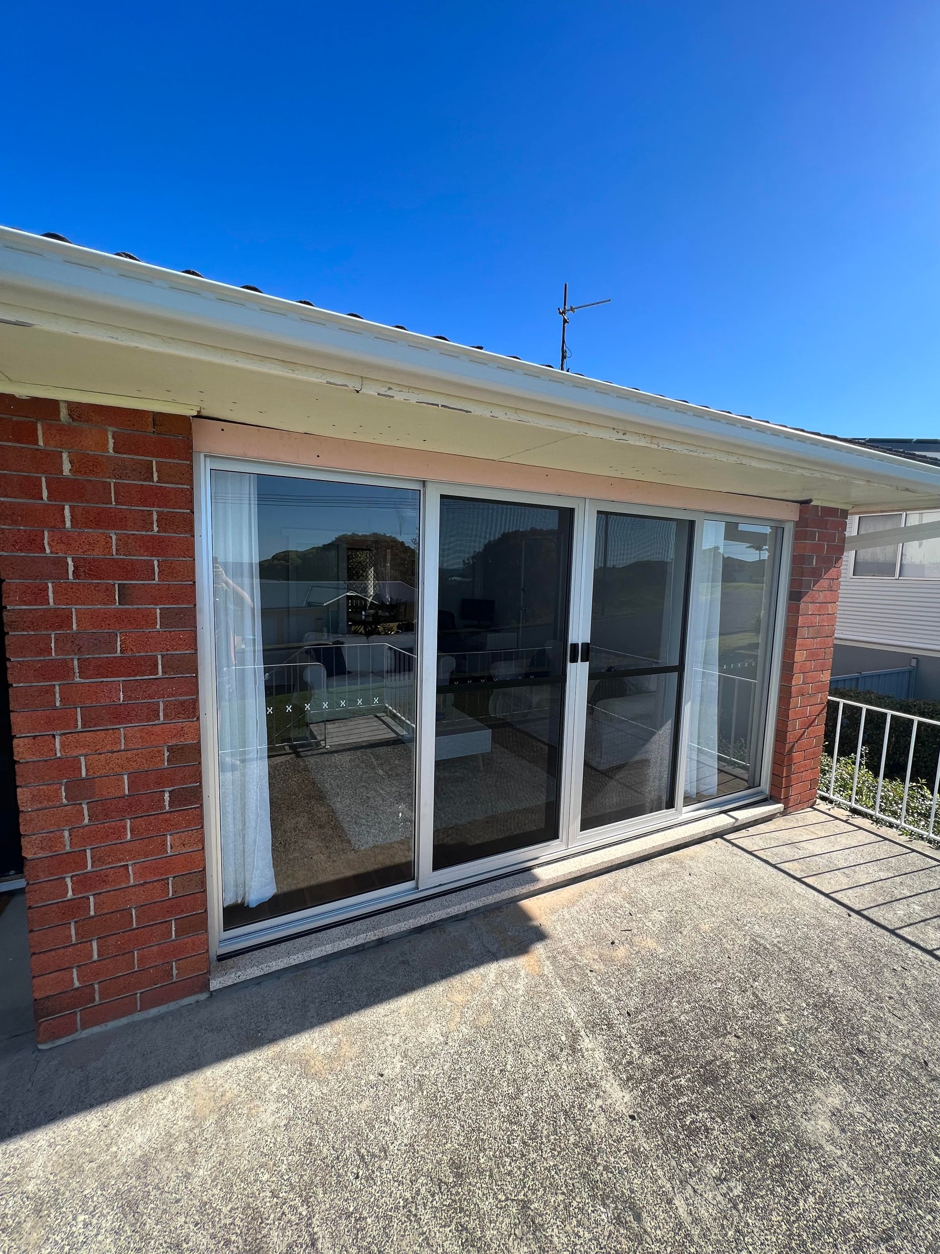 A brick house with sliding glass doors and a blue sky in the background — Glass 24/7 In Taree, NSW