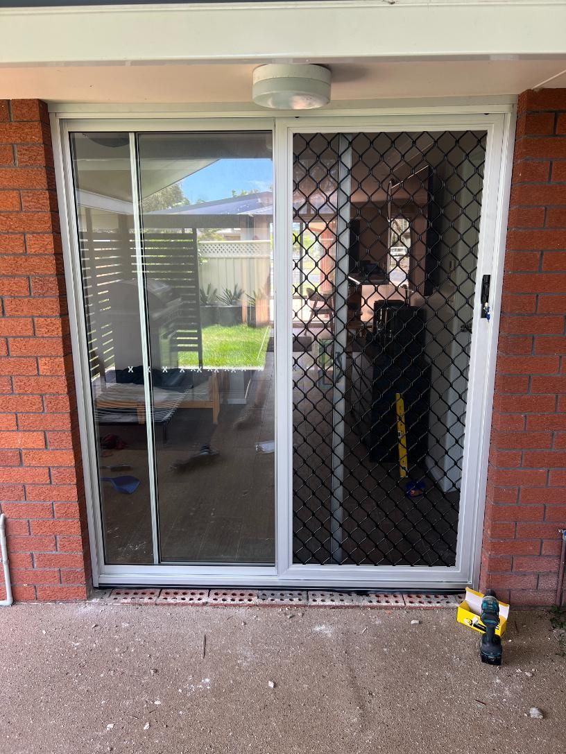 A Sliding Glass Door Is Being Installed On A Brick Building — Glass 24/7 In Taree, NSW