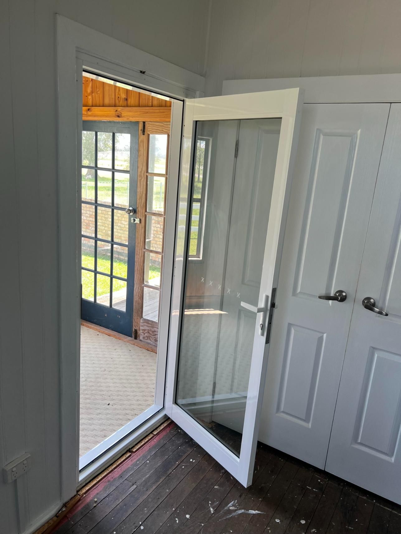 A White Door With A Glass Window Is Open In A Room With A Wooden Floor — Glass 24/7 In Taree, NSW
