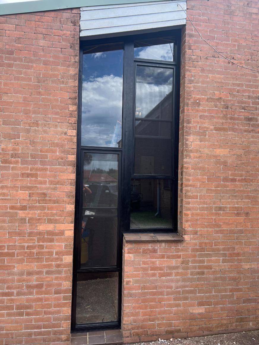 A Brick Building With A Black Window On The Side Of It — Glass 24/7 In Forster, NSW
