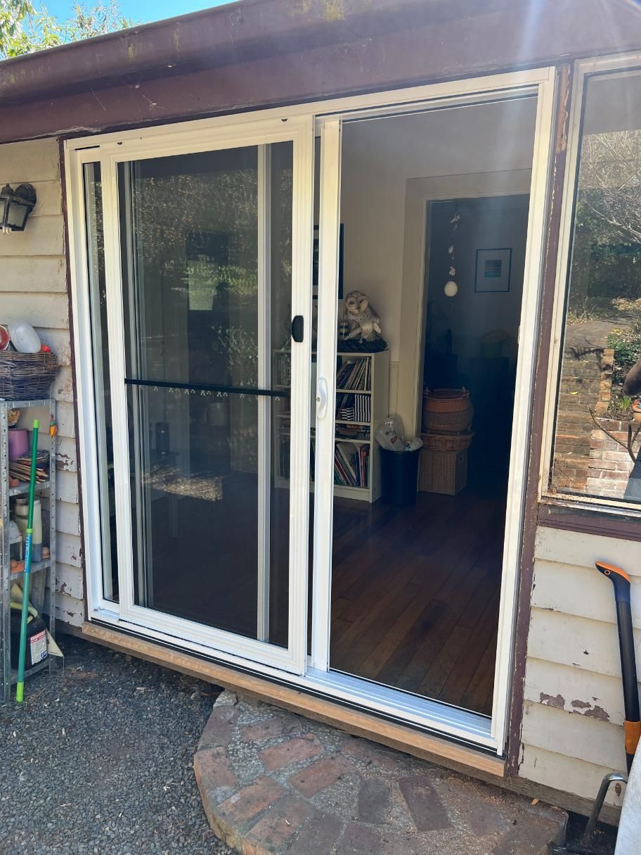 A White Sliding Glass Door Is Open To A Living Room — Glass 24/7 In Taree, NSW