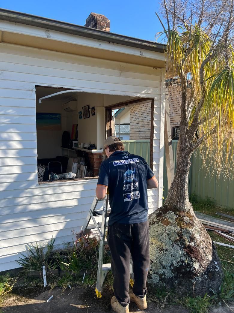A Man Is Standing In Front Of A House With A Ladder — Glass 24/7 In Taree, NSW