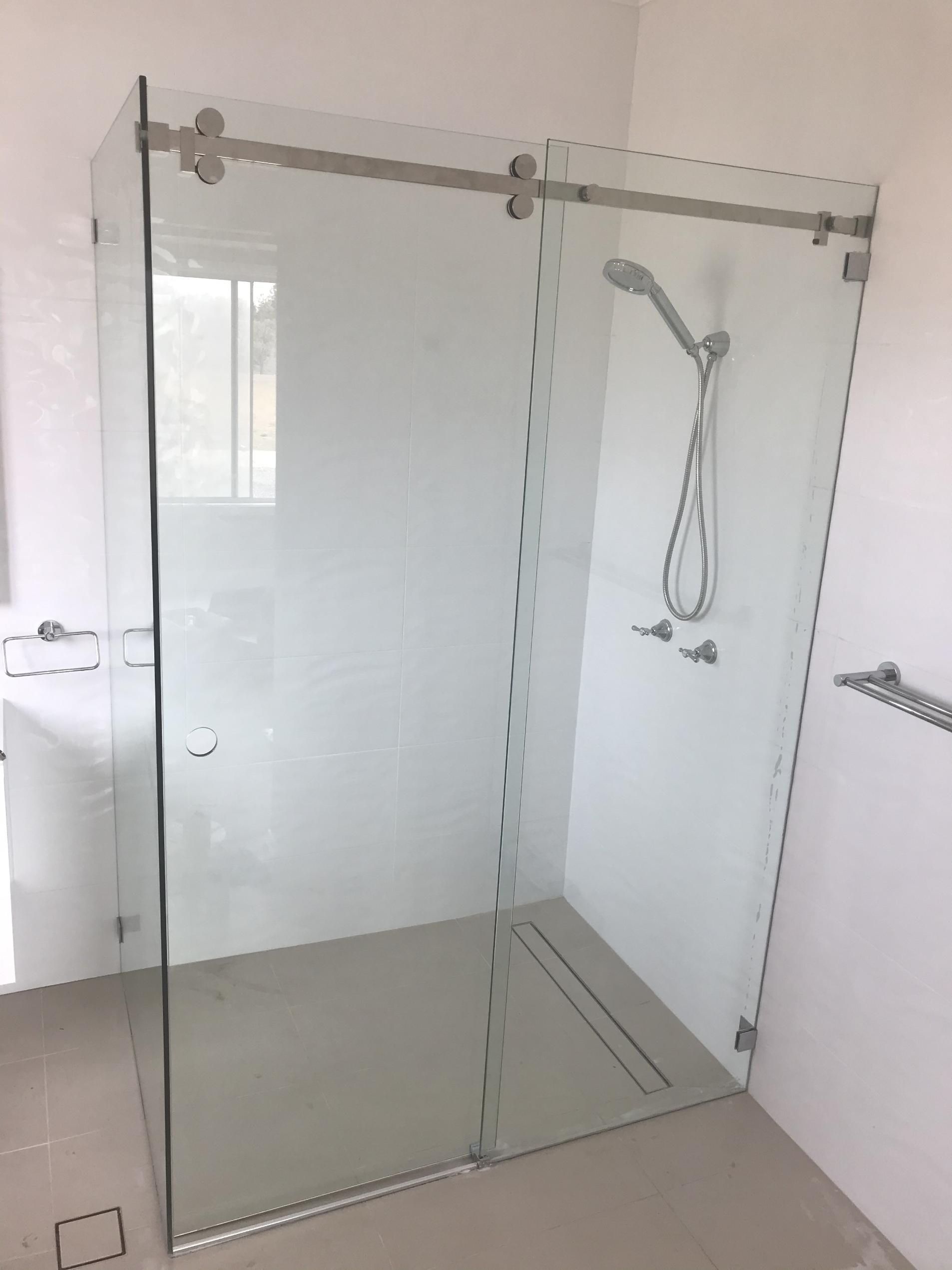A Bathroom With A Sliding Glass Shower Door And A Shower Head — Glass 24/7 In Taree, NSW