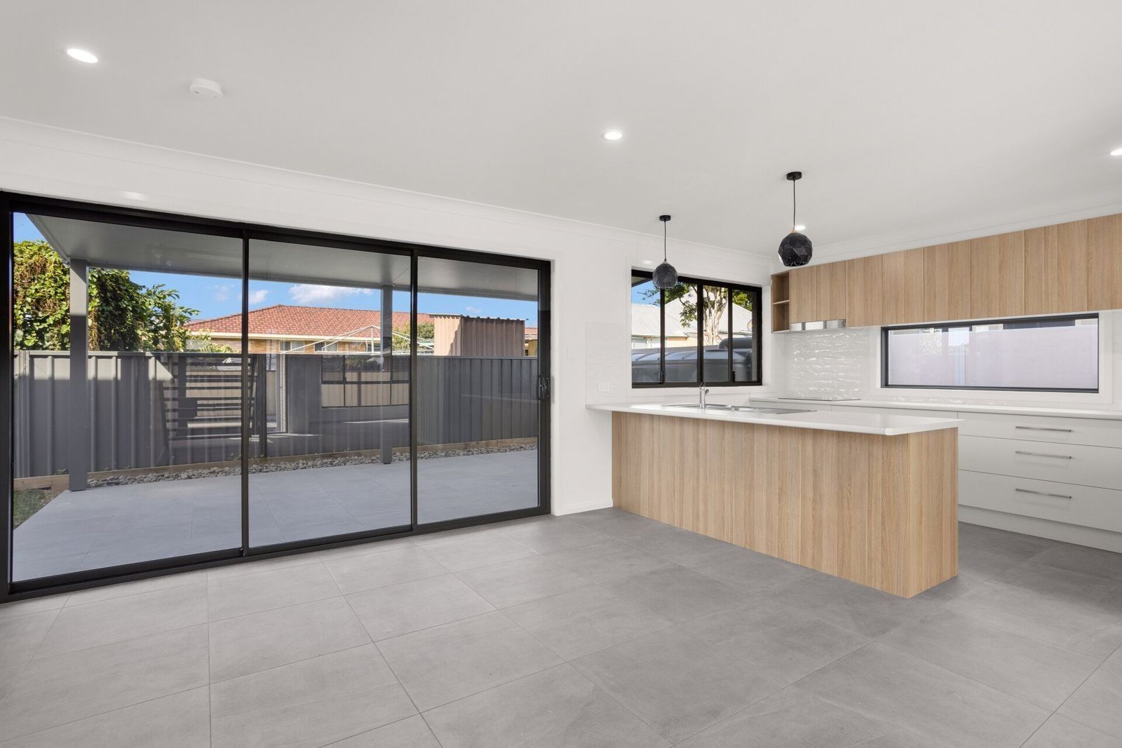 An Empty Kitchen With Sliding Glass Doors And A Large Island — Glass 24/7 In Taree, NSW