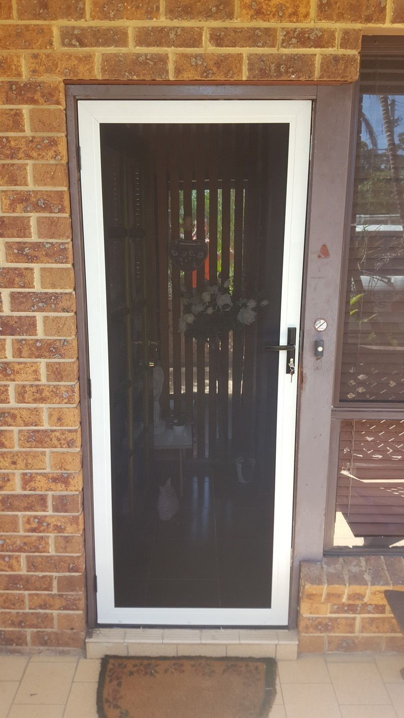 A White Screen Door Is Sitting On A Porch Next To A Brick Wall — Glass 24/7 In Pacific Palms, NSW