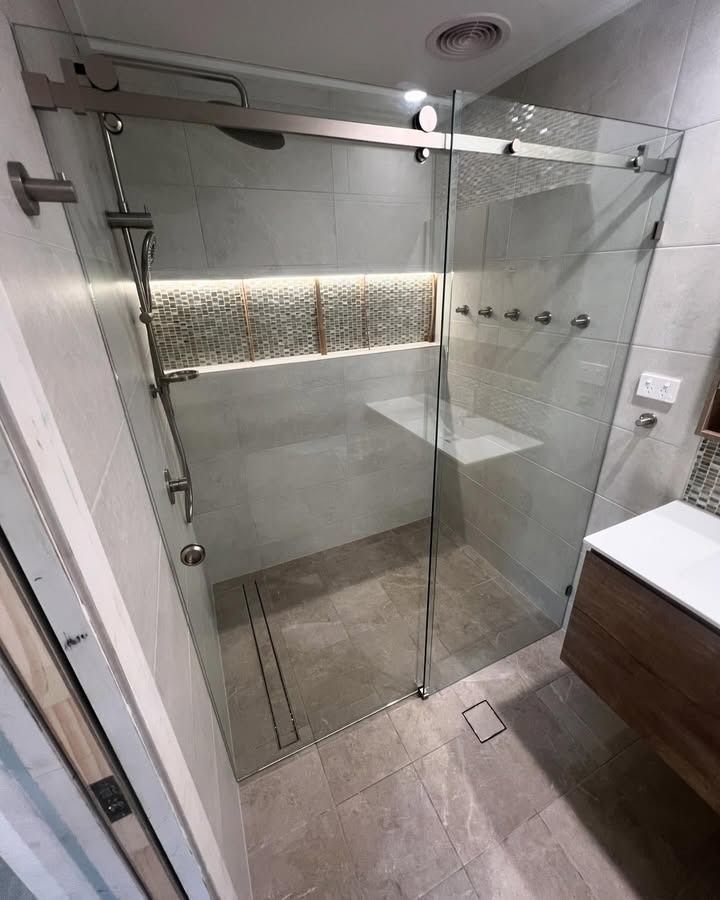 A Bathroom With A Sliding Glass Shower Door And A Sink — Glass 24/7 In Tuncurry, NSW
