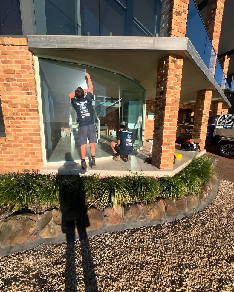 A Group Of Men Are Working On A Large Window On The Side Of A Building — Glass 24/7 In Pacific Palms, NSW