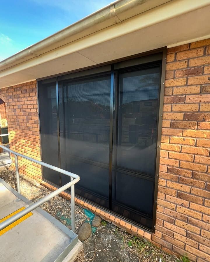 A Brick Building With A Sliding Glass Door And A Railing — Glass 24/7 In Harrington, NSW