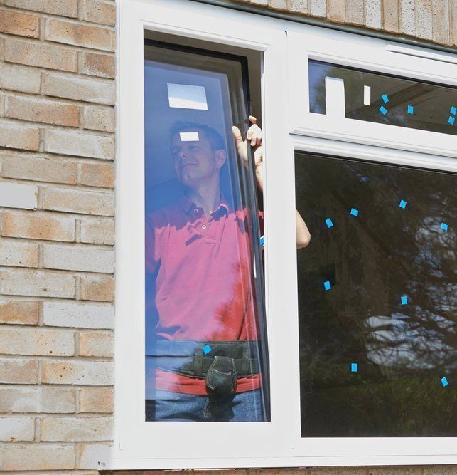 A Man In A Red Shirt Is Looking Out Of A Window — Glass 24/7 In Gloucester, NSW
