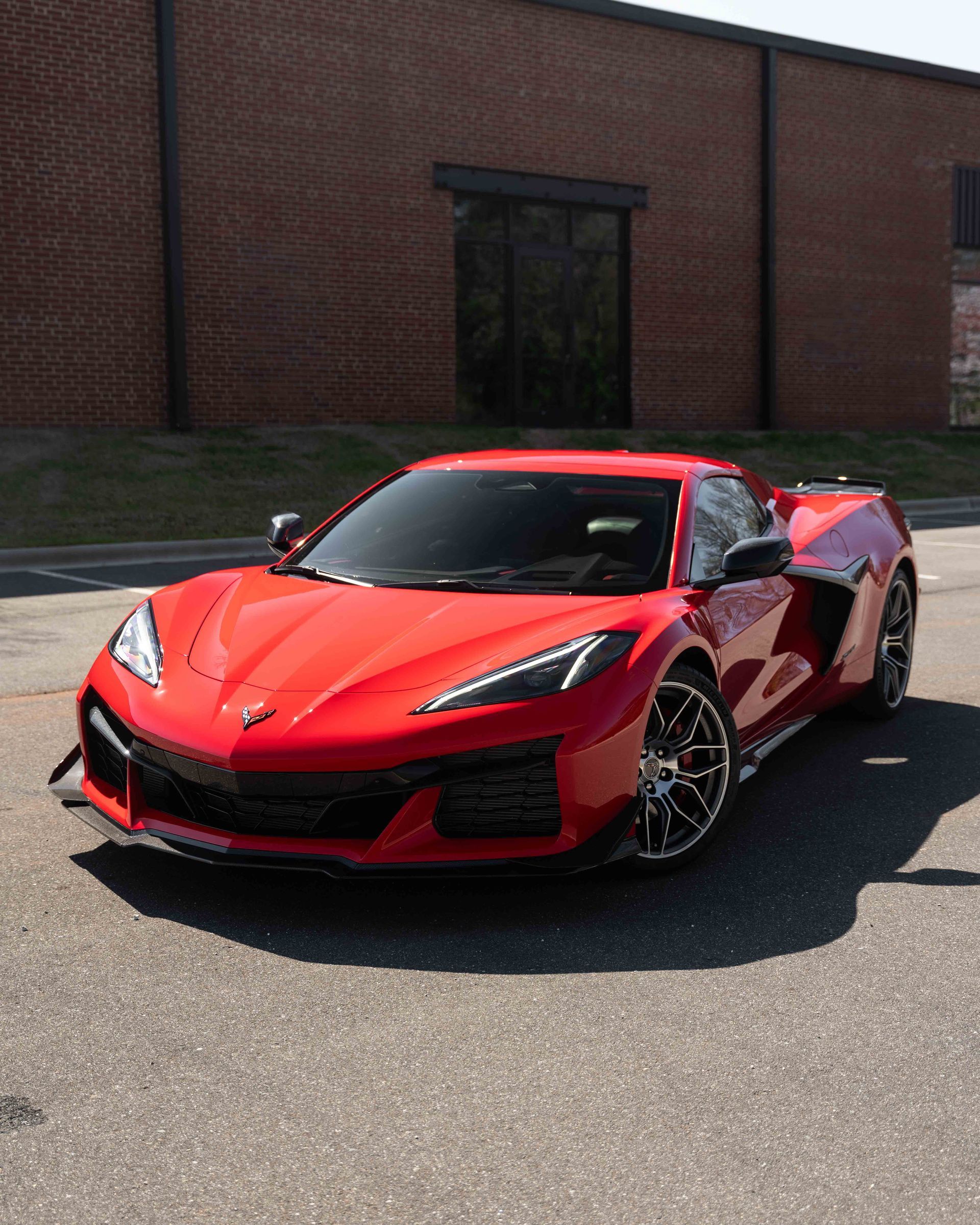 A red sports car is parked in front of a brick building