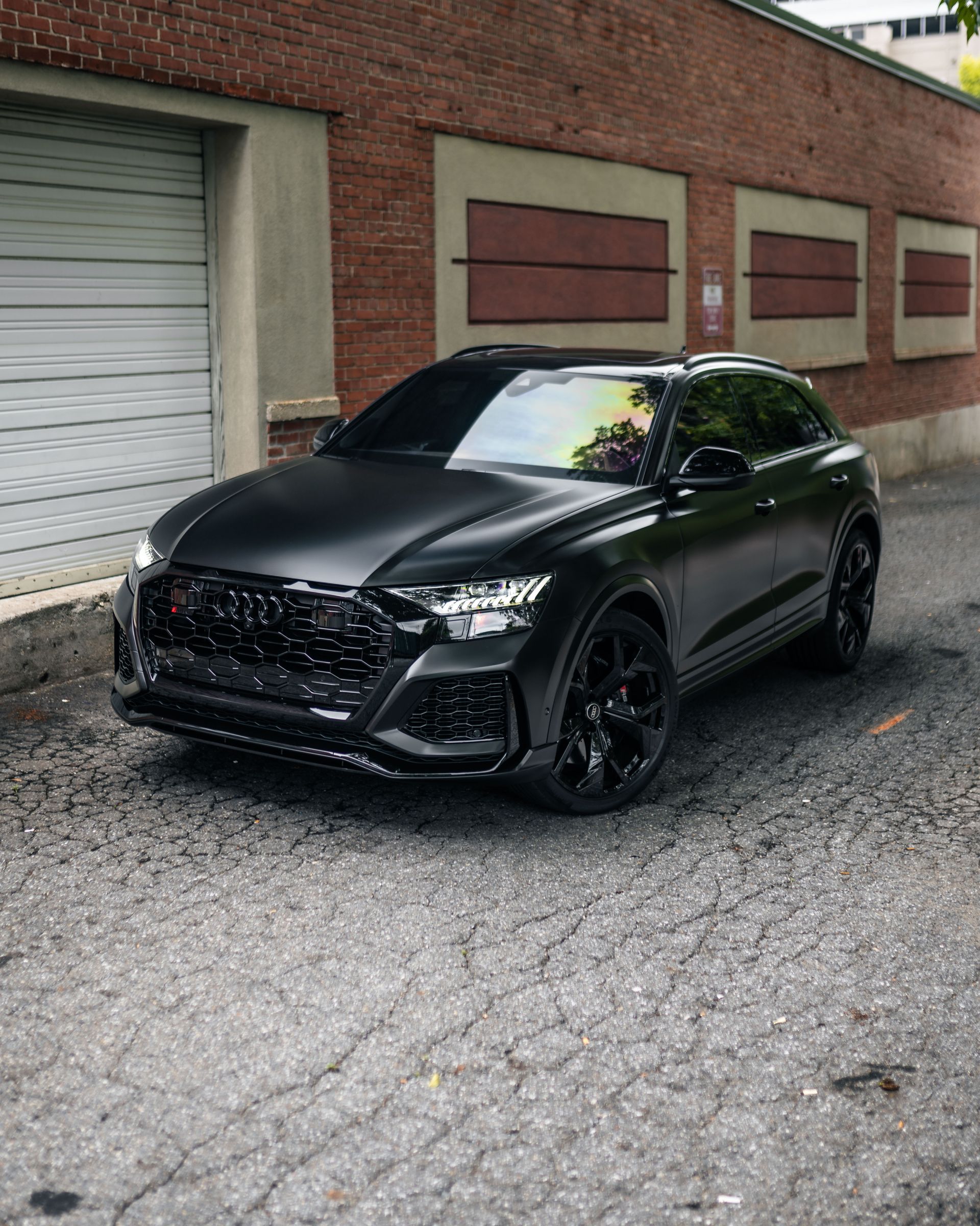 A black audi q8 is parked in front of a brick building.