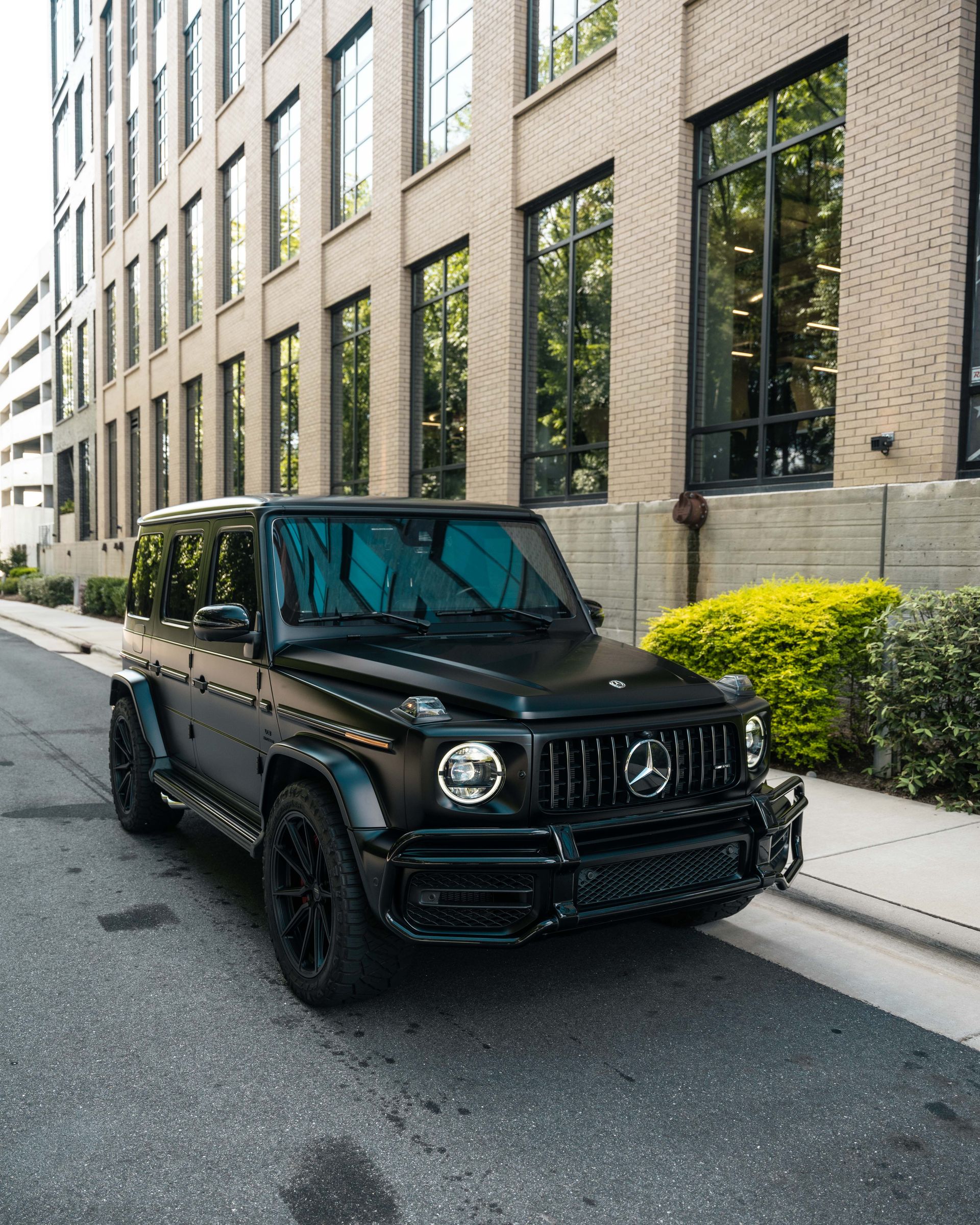 A black mercedes is parked on the side of the road in front of a building