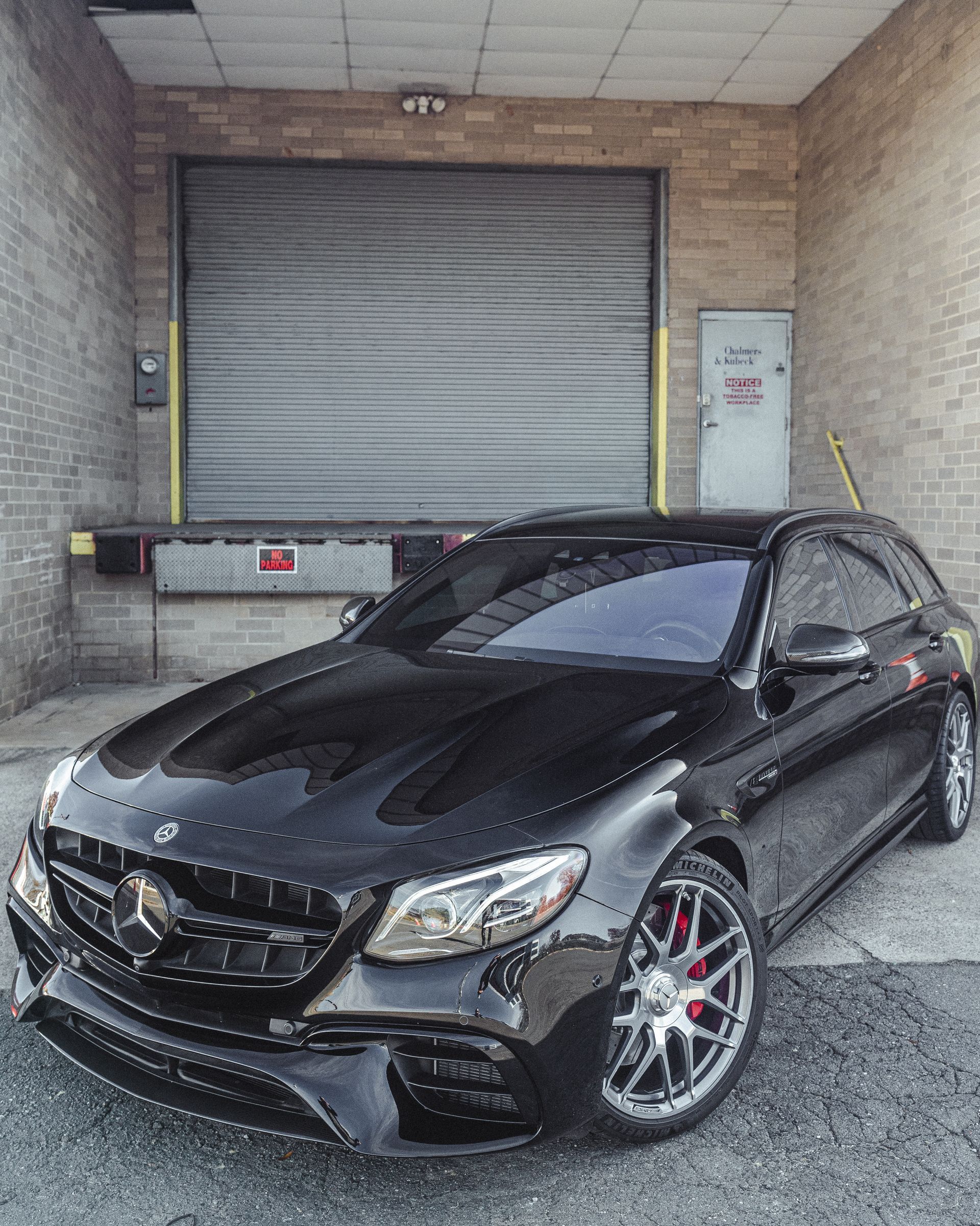A black mercedes benz is parked in front of a garage door.
