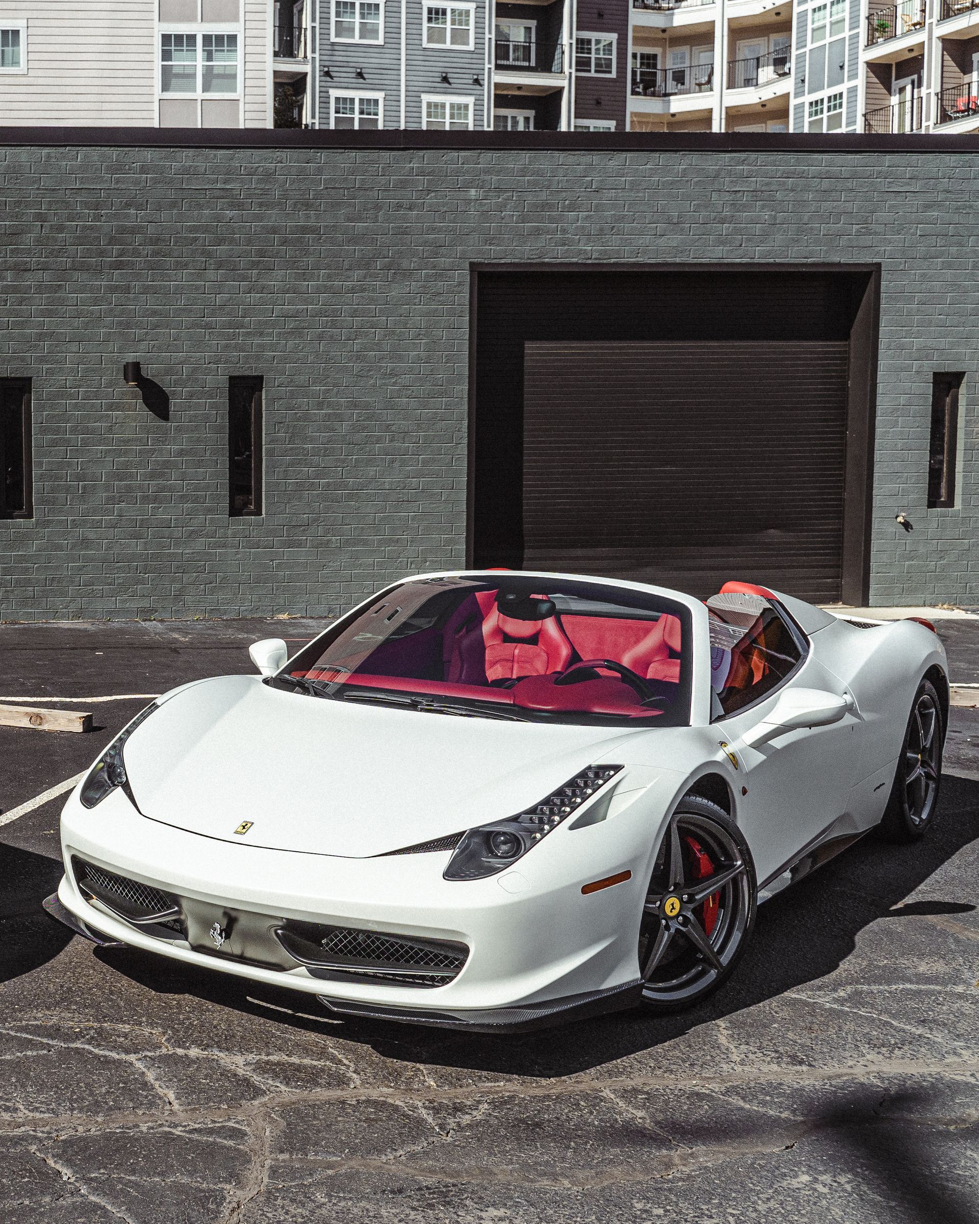A white sports car is parked in front of a building.