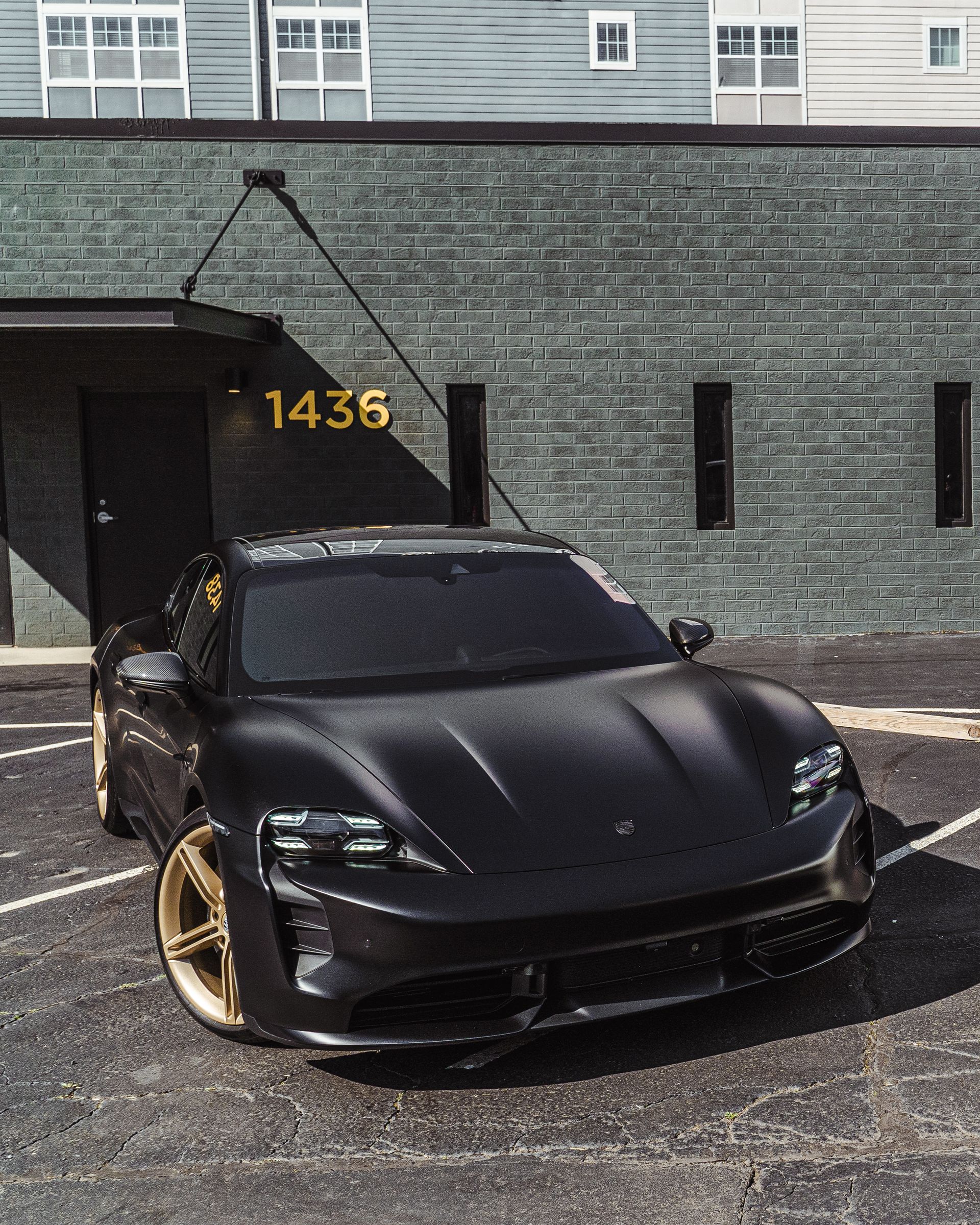A black sports car is parked in front of a building with the number 1434 on it.