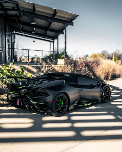 A black lamborghini huracan is parked in front of a building.