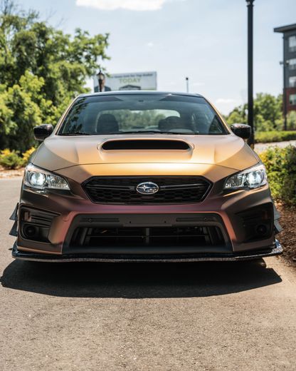 A gold subaru is parked on the side of the road