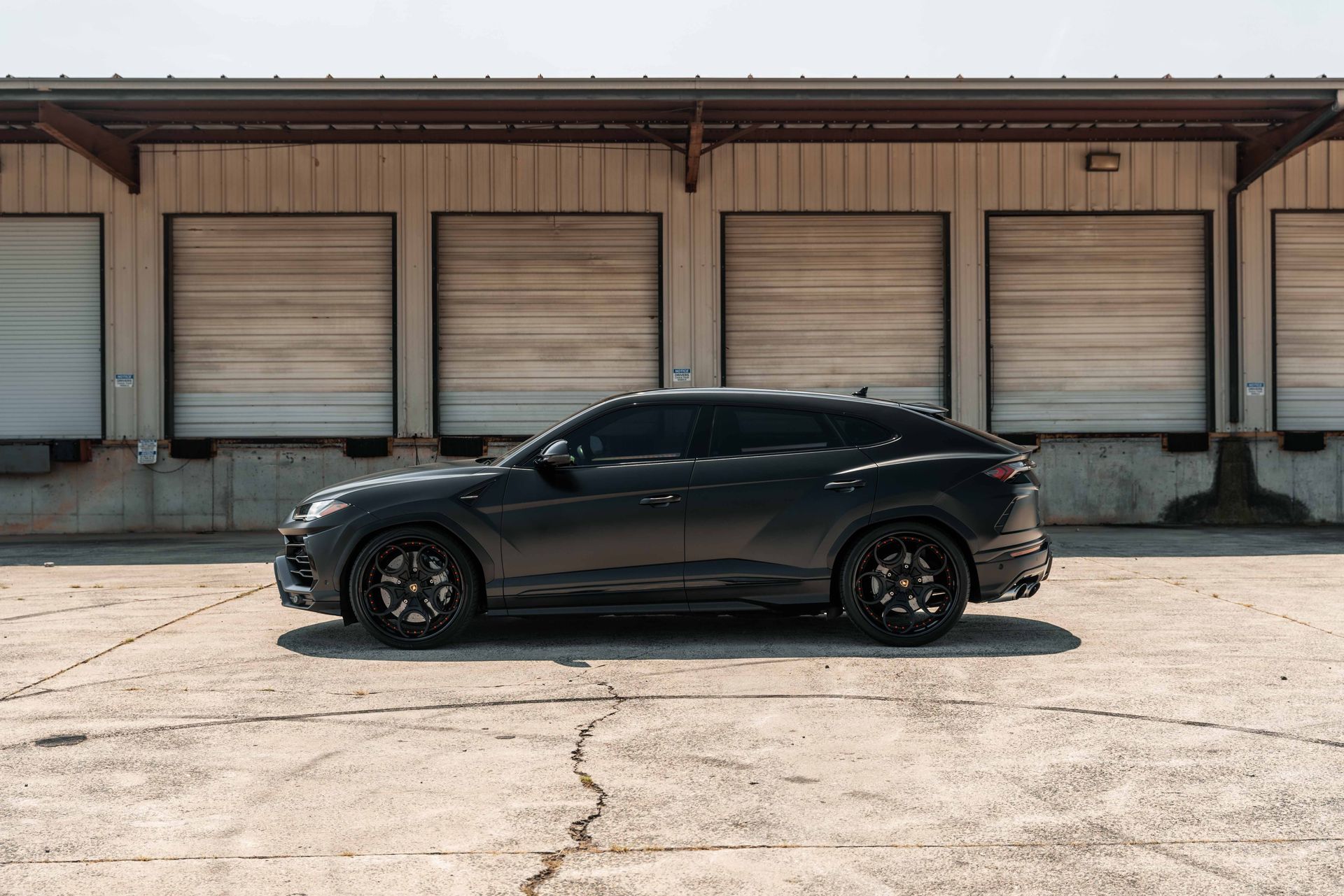 A black car is parked in front of a warehouse.