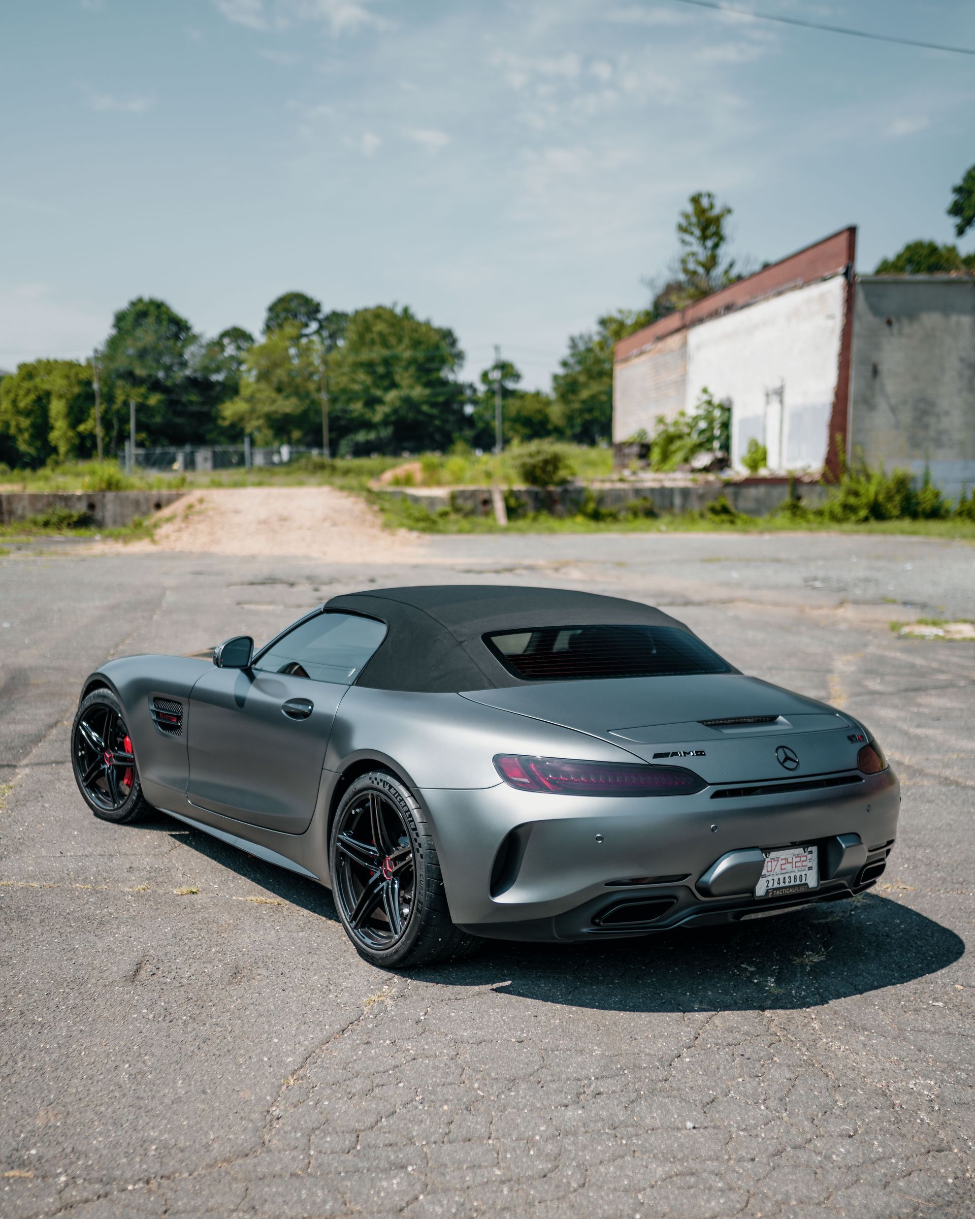 A silver sports car with a convertible top is parked in a parking lot.