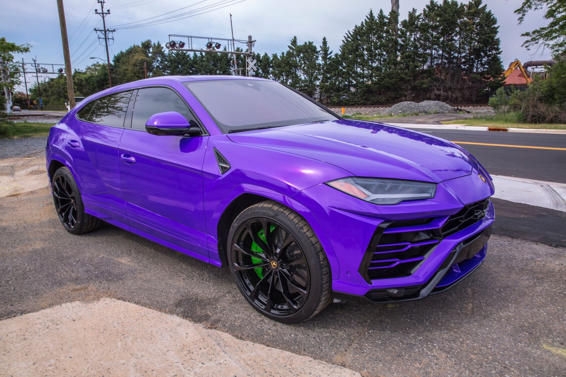 A purple lamborghini urus is parked on the side of the road.