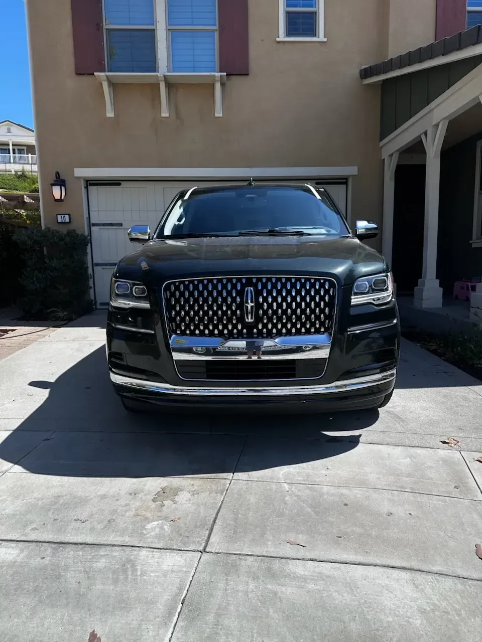 A luxury SUV parked in a residential driveway with clear auto glass visible on the front windshield and windows by Shine City