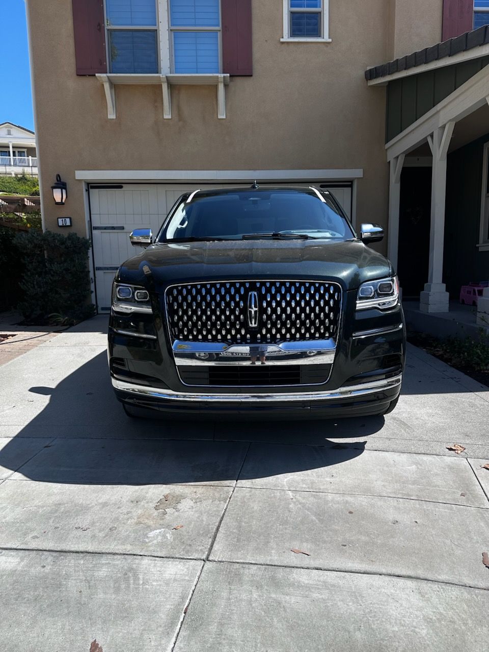 A luxury SUV parked in a residential driveway with clear auto glass visible on the front windshield and windows by Shine City